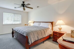 A bedroom with a bed, bedside tables, a lamp, a ceiling fan, and a window with blinds.