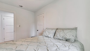 Una camera da letto con un letto, due porte e un lampadario.