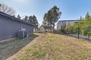 Ein Wohngebiet mit einem Haus, einem eingezäunten Garten und einem großen Gebäude im Hintergrund.
