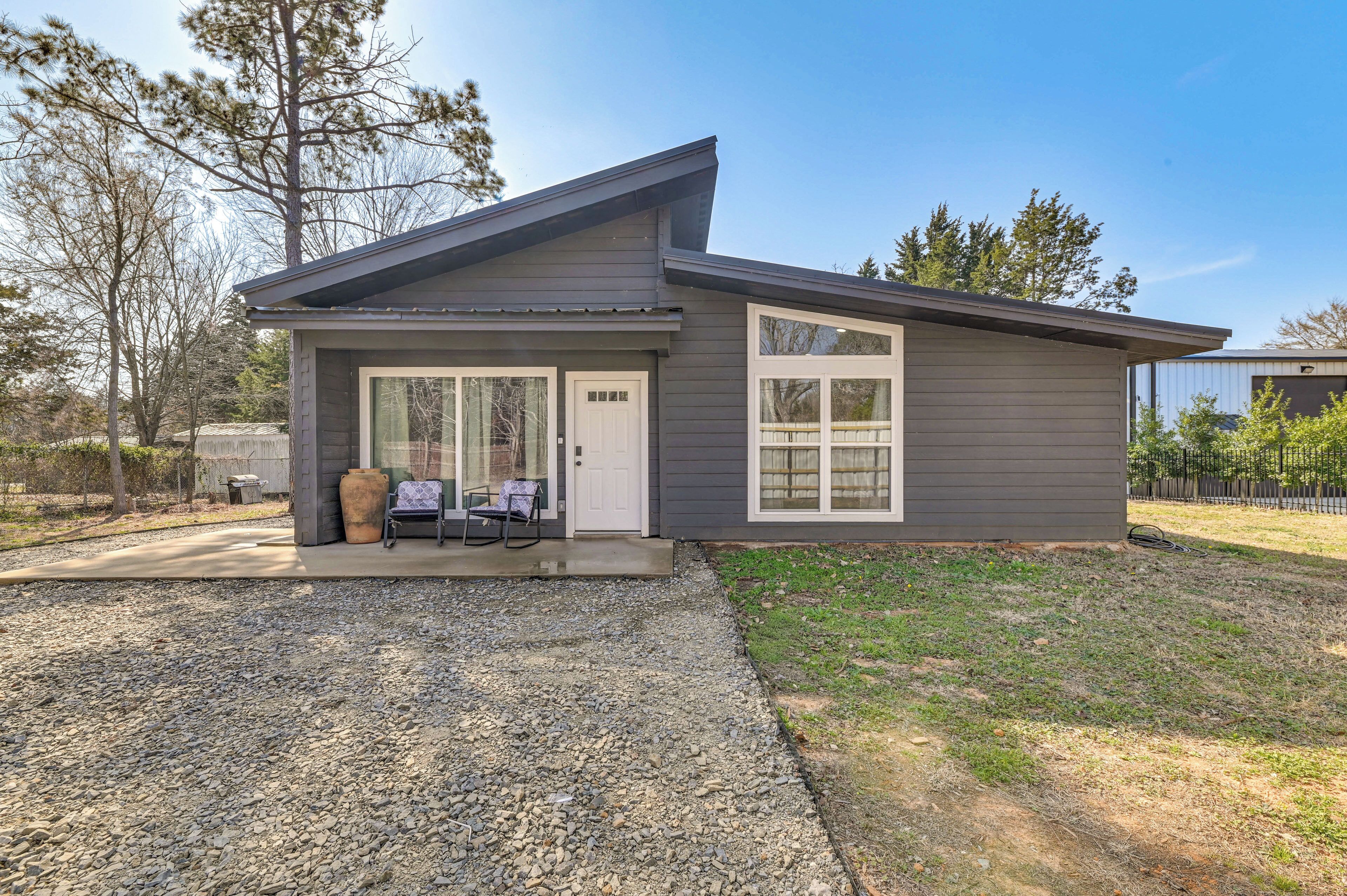 A modern two-story house with a grey exterior, a covered porch, and a gravel driveway.