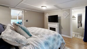 Een slaapkamer met een bed, een televisie en een open haard.