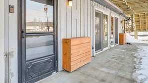 Een gebouw met een grote zwarte deur, een houten bankje en een overdekt terras.