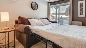 Hotelkamer met een bed, een nachtkastje, een lamp, een klok aan de muur en een raam met uitzicht.