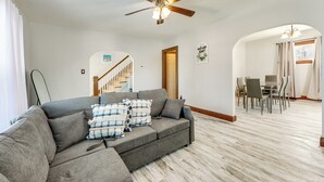 A living room with a gray sectional sofa, a ceiling fan, and a dining area with a table and chairs. - 2 Mi to Syracuse University: Quiet Family Home (Syracuse)