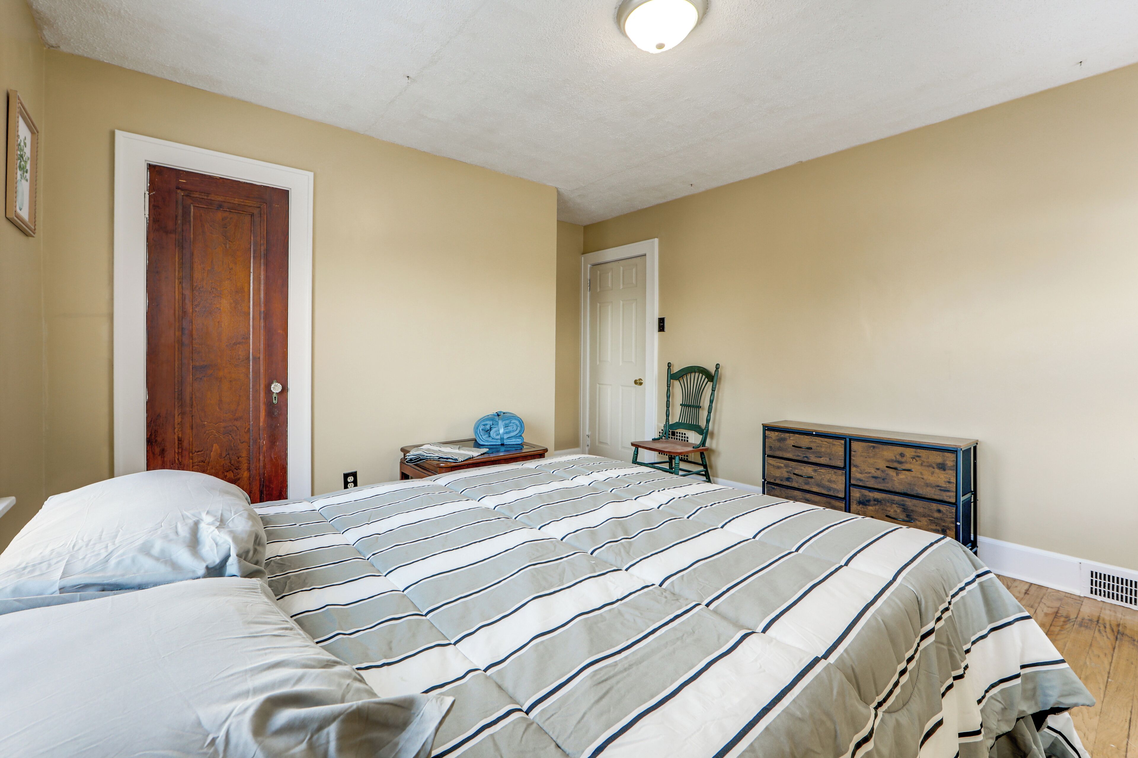 Un dormitorio con cama, cómoda, silla y puerta.