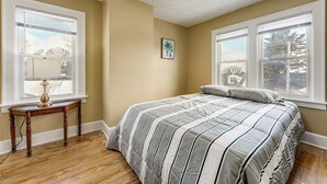 A bedroom with a bed, two windows, a small table, and a picture on the wall. - 2 Mi to Syracuse University: Quiet Family Home (Syracuse)