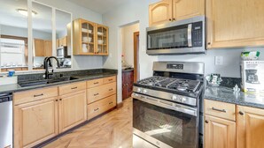 A modern kitchen with wooden cabinets, a stainless steel stove, a microwave, and a dishwasher. - 2 Mi to Syracuse University: Quiet Family Home (Syracuse)