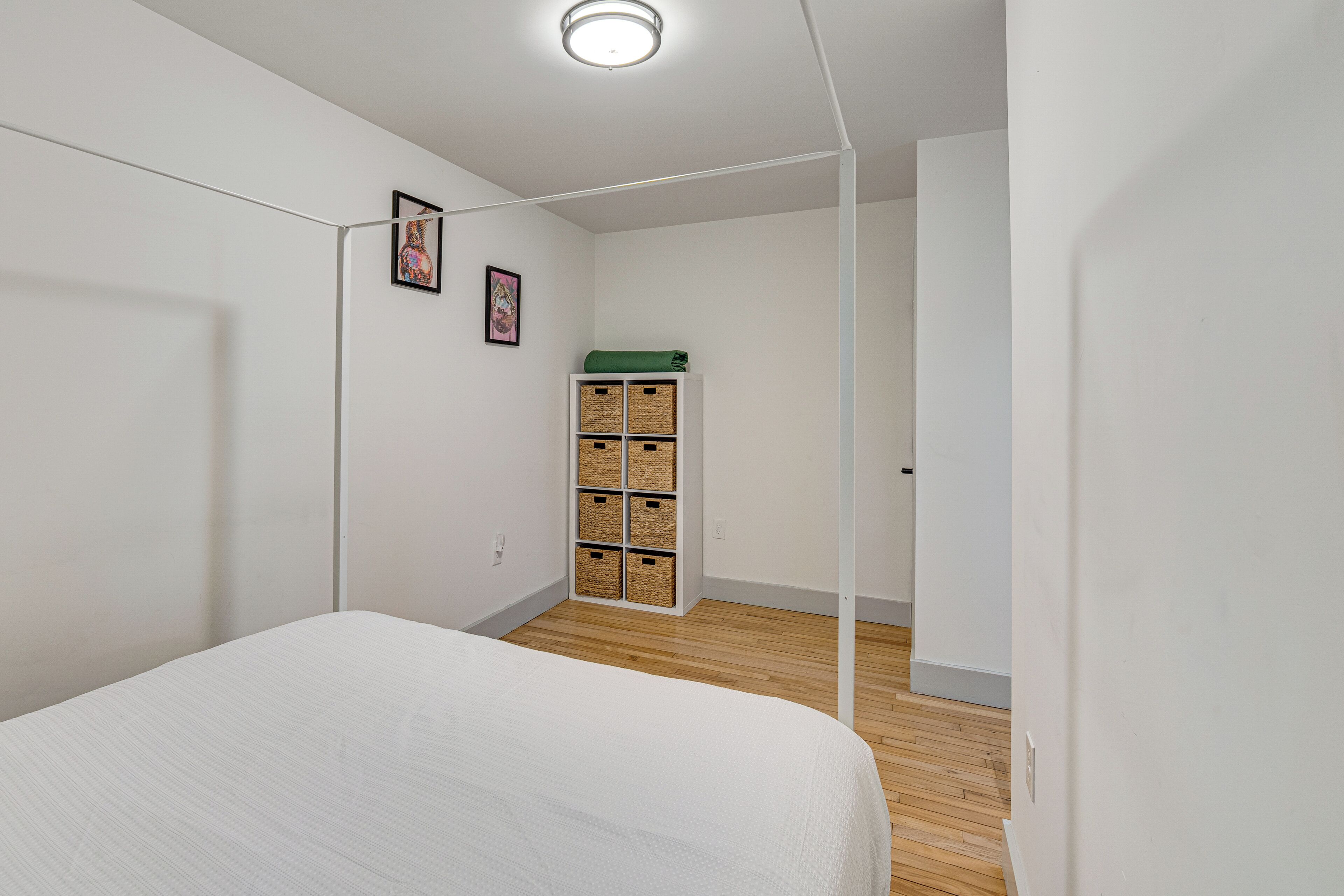Un dormitorio con cama, suelo de madera, un armario blanco y una toalla verde encima.