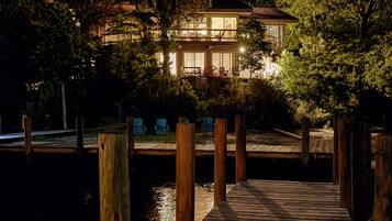 A waterfront property with a wooden dock leading to a house with a balcony.