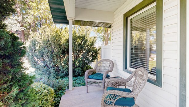 A porch with wicker chairs and a white exterior wall.