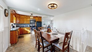 Une cuisine spacieuse avec des meubles de rangement en bois, une table à manger avec des chaises et un luminaire au plafond.