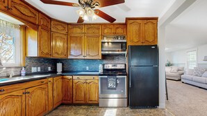 A kitchen with wooden cabinets, a stainless steel oven, and a black refrigerator.