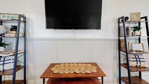 A room with a wooden table displaying a grid of round objects, flanked by metal shelving units with various decorative items.