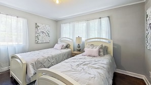 A bedroom with two single beds, a nightstand with a lamp, and a wall-mounted artwork. - On-site Trails! 'serenity Acres Retreat' in Macon (Macon)