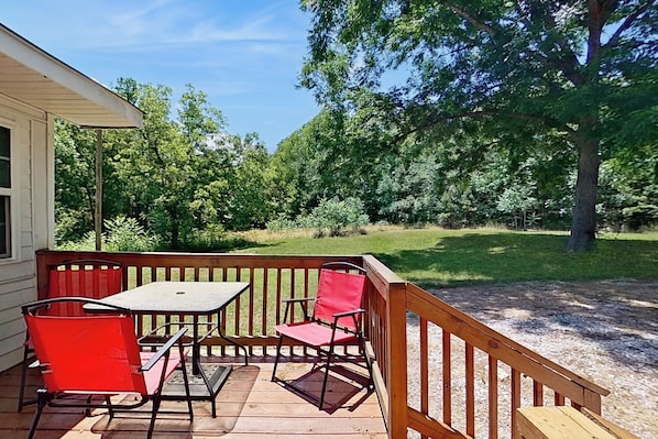 A wooden deck with a table and two chairs, surrounded by a wooden railing. - On-site Trails! 'serenity Acres Retreat' in Macon (Macon)