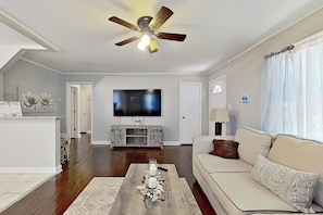 Un salon doté d’un ventilateur de plafond, d ’un téléviseur à écran plat, d’un canapé et d’une table basse.