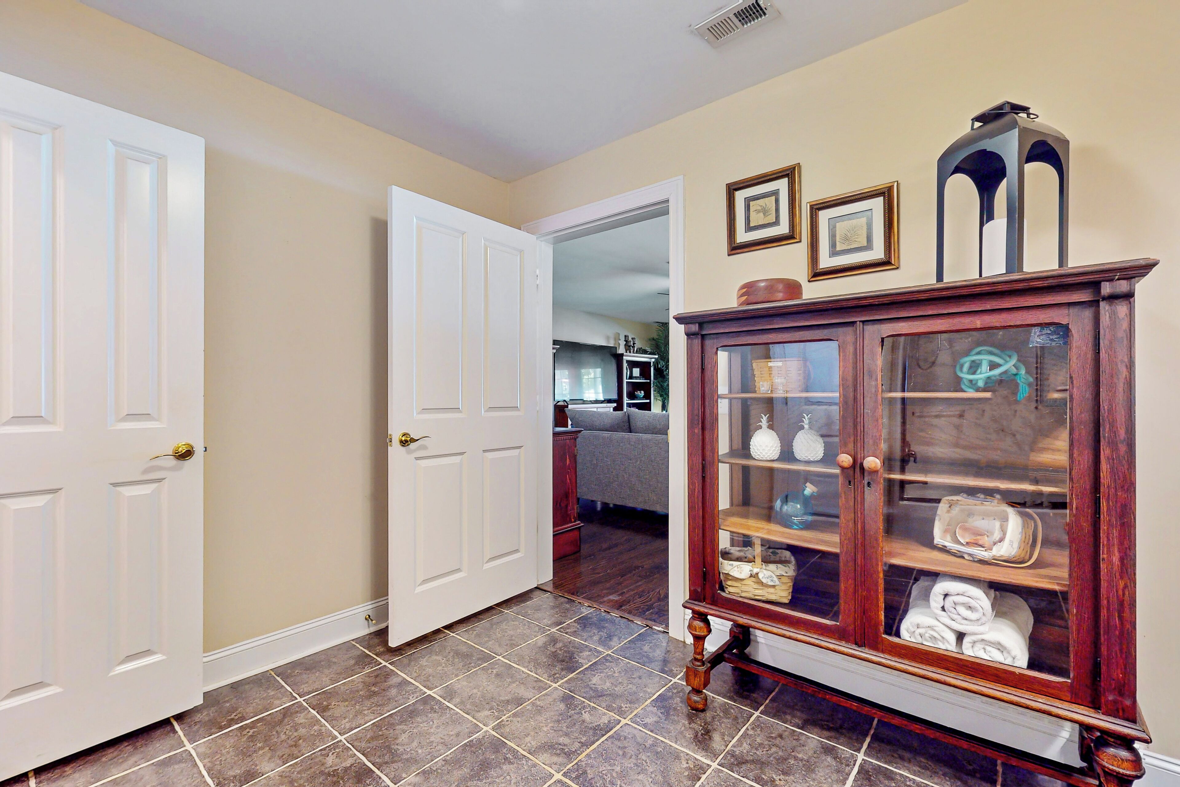 A hallway with a wooden cabinet, a white door, and a tiled floor.