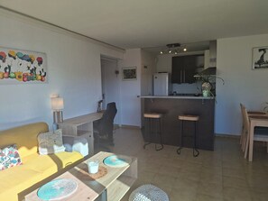 A compact living space with a dining area, kitchen, and a sofa with a patterned cushion. - Near Cannes, with air conditioning, private parking and balcony Pets welcome (Le Cannet)