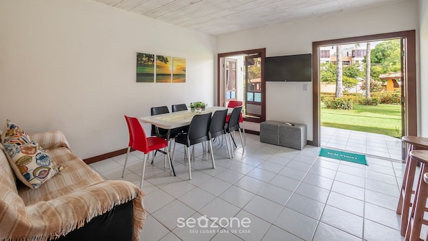 Ein geräumiges Zimmer mit Essbereich, einer Couch und einem an der Wand montierten Fernseher.