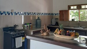 A kitchen with a gas stove, a water dispenser, and a fruit bowl on the counter.