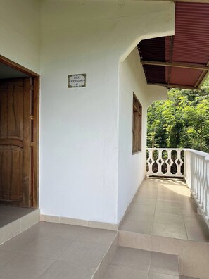 A corridor with a wooden door, a sign reading "CASA MAJANICHO 45", and a balcony with a white railing.