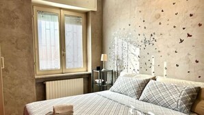 Un dormitorio con una cama, una mesita de noche, una lámpara y una ventana con persianas.