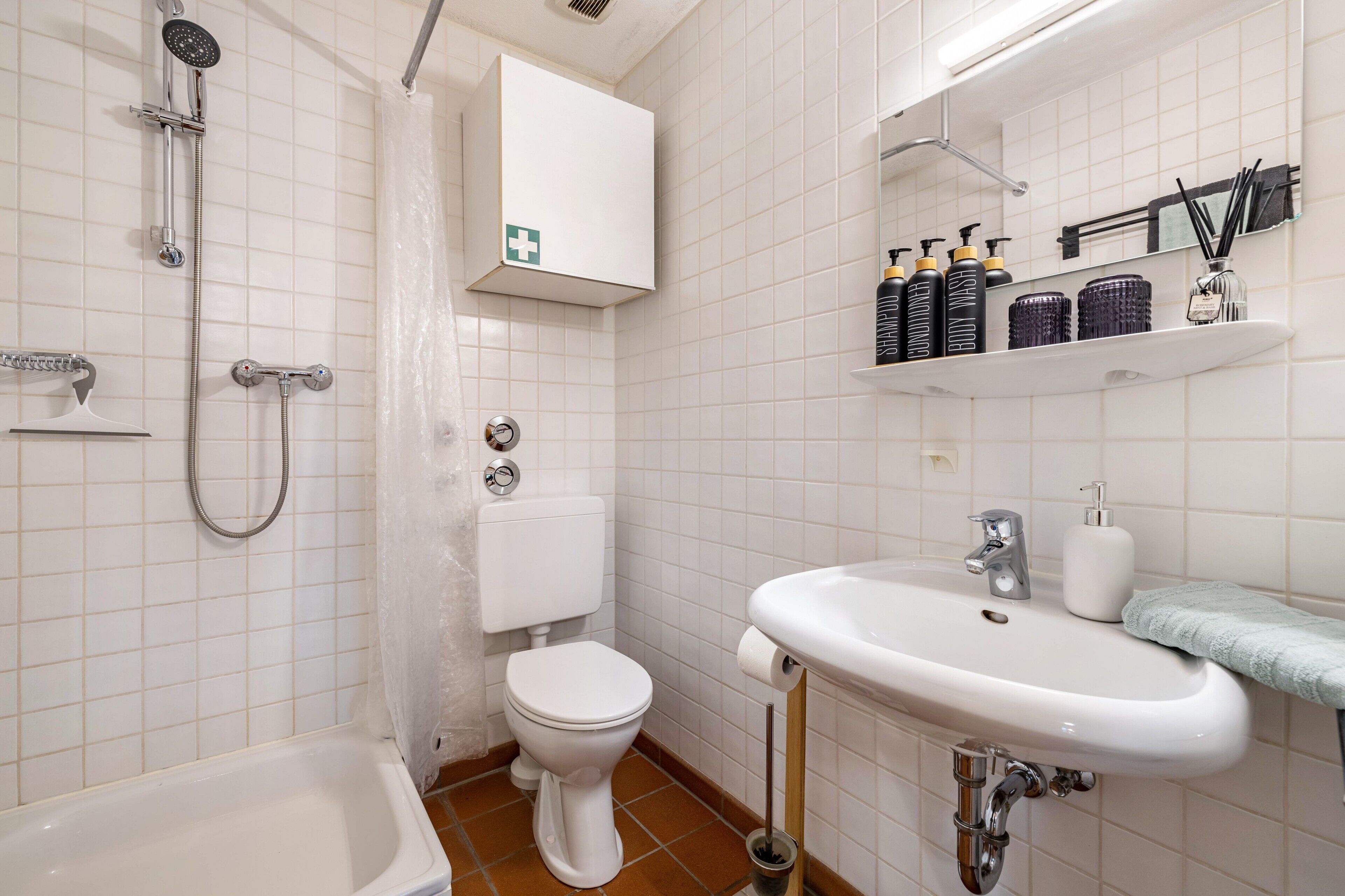 Une salle de bain équipée de toilettes, d’une douche, d’un lavabo et d’un meuble contenant des articles de toilette.