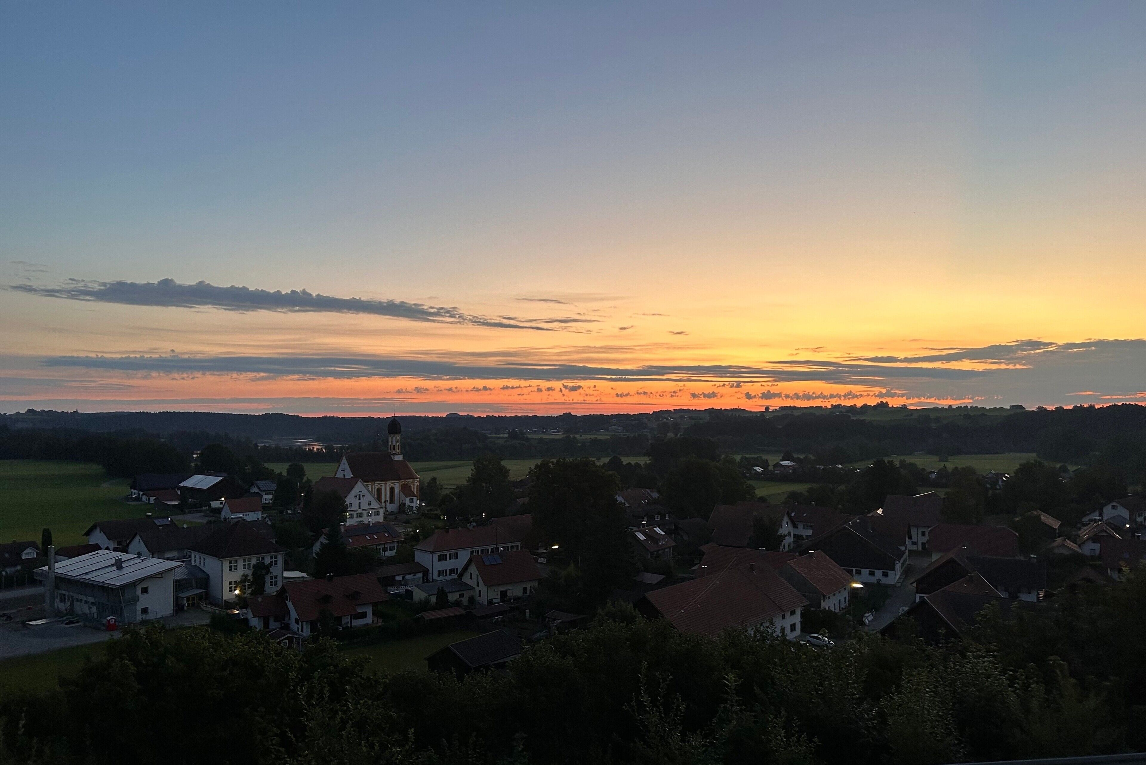 Ein Dorf mit traditioneller Architektur, einer Kirche und blauem Himmel.