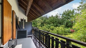 Un balcon avec une balustrade en bois, une table et une chaise.