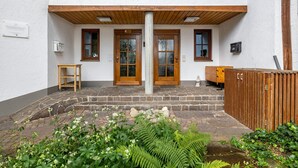 Une entrée d’immeuble avec une porte en bois, une petite table et un banc.