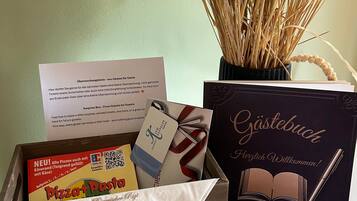A wooden box with a pizza box, a gift card, a card with a book illustration, and a vase with dried plants.