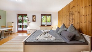 Une chambre à coucher avec un lit, un mur en bois, une fenêtre, un radiateur et une chaise.
