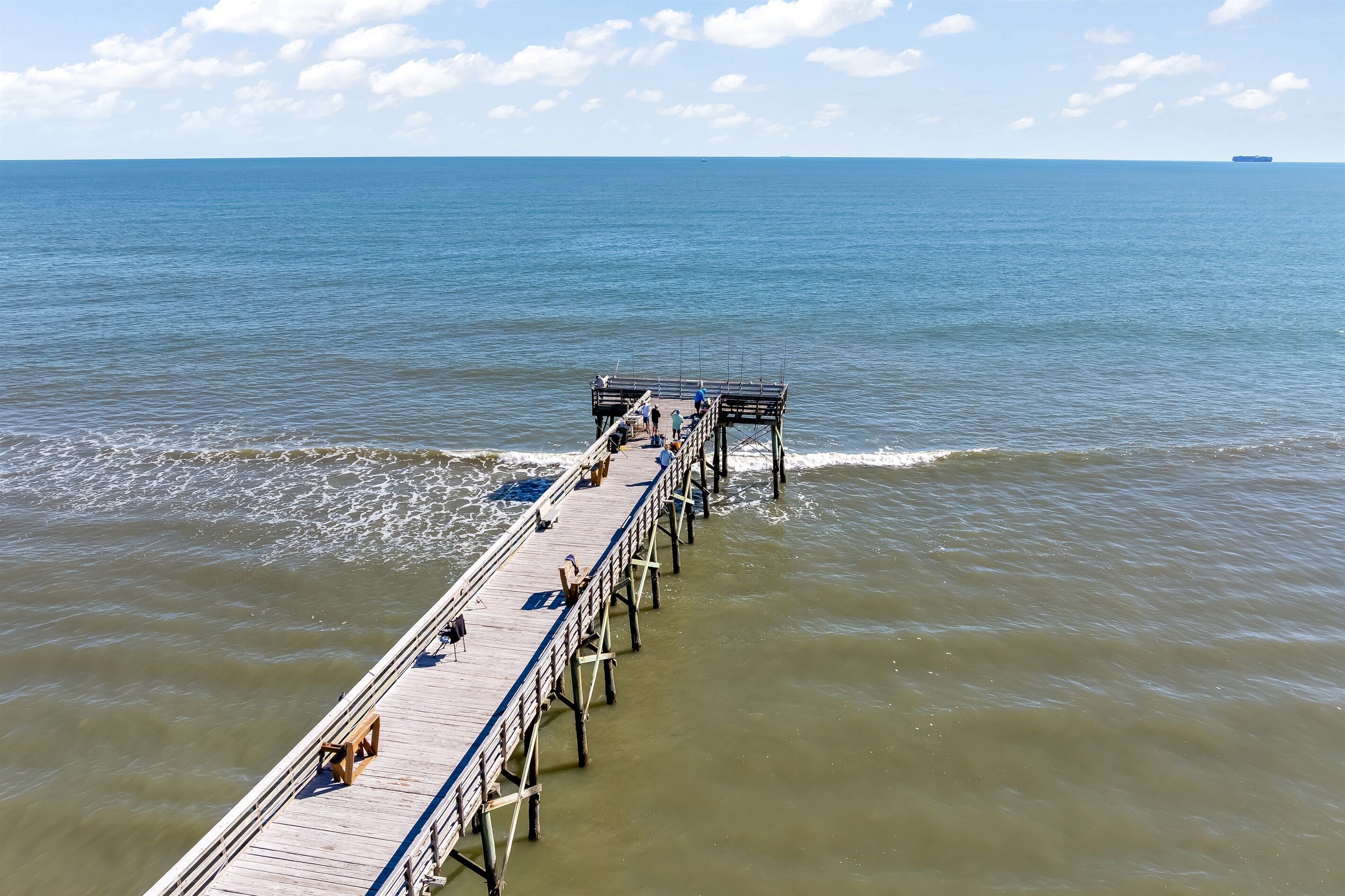 A pier extending into calm waters with a clear sky.