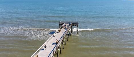 A pier extending into calm waters with a clear sky.