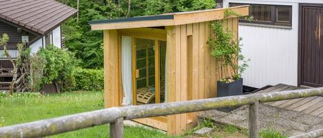 Une structure en bois dotée d’une porte et d’une petite fenêtre, entourée de verdure.