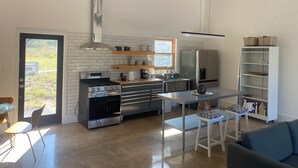 Une cuisine moderne dotée d’un îlot central, d’appareils électroménagers intégrés et d’une fenêtre donnant sur un jardin.
