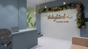 Un espace d’accueil au design moderne, comprenant un comptoir de réception, un mur agrémenté d’une composition florale et un message de bienvenue.