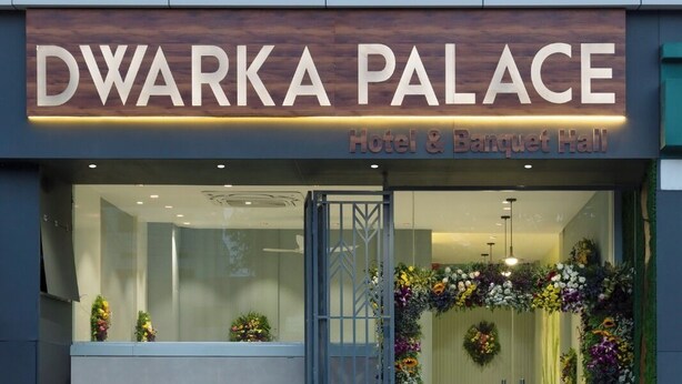 L’extérieur de l’hôtel Dwarka Palace et de sa salle de réception se distingue par sa façade moderne, son entrée accueillante et une décoration florale à l’entrée.