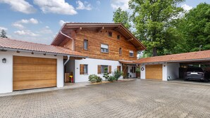 Une maison à deux étages, avec un toit en tuiles, une allée pavée et un garage.