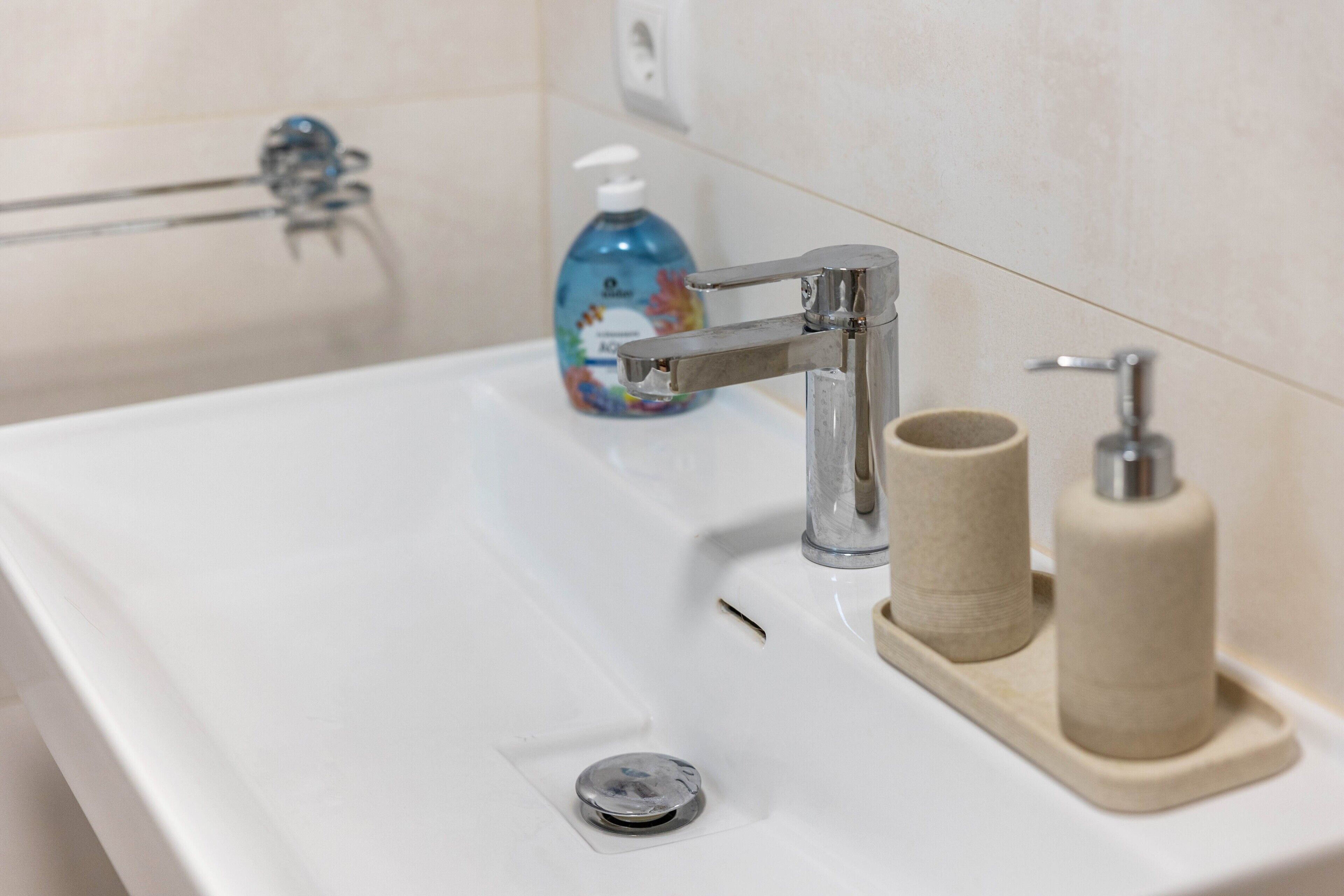 Ein Badezimmerwaschbecken mit einem Chromarmaturen, einem Seifenspender und zwei Toilettenpapierrollen.