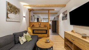 Un salon moderne comprenant un canapé, une table basse, un meuble en bois et un téléviseur à écran plat.