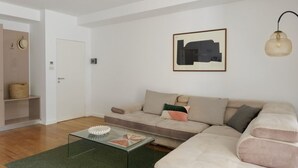 Un soggiorno moderno con un divano color beige, un tavolino in vetro e un'opera d'arte astratta incorniciata al muro.