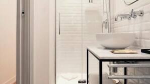 Een moderne badkamer met een witte wastafel, spiegel en douche.