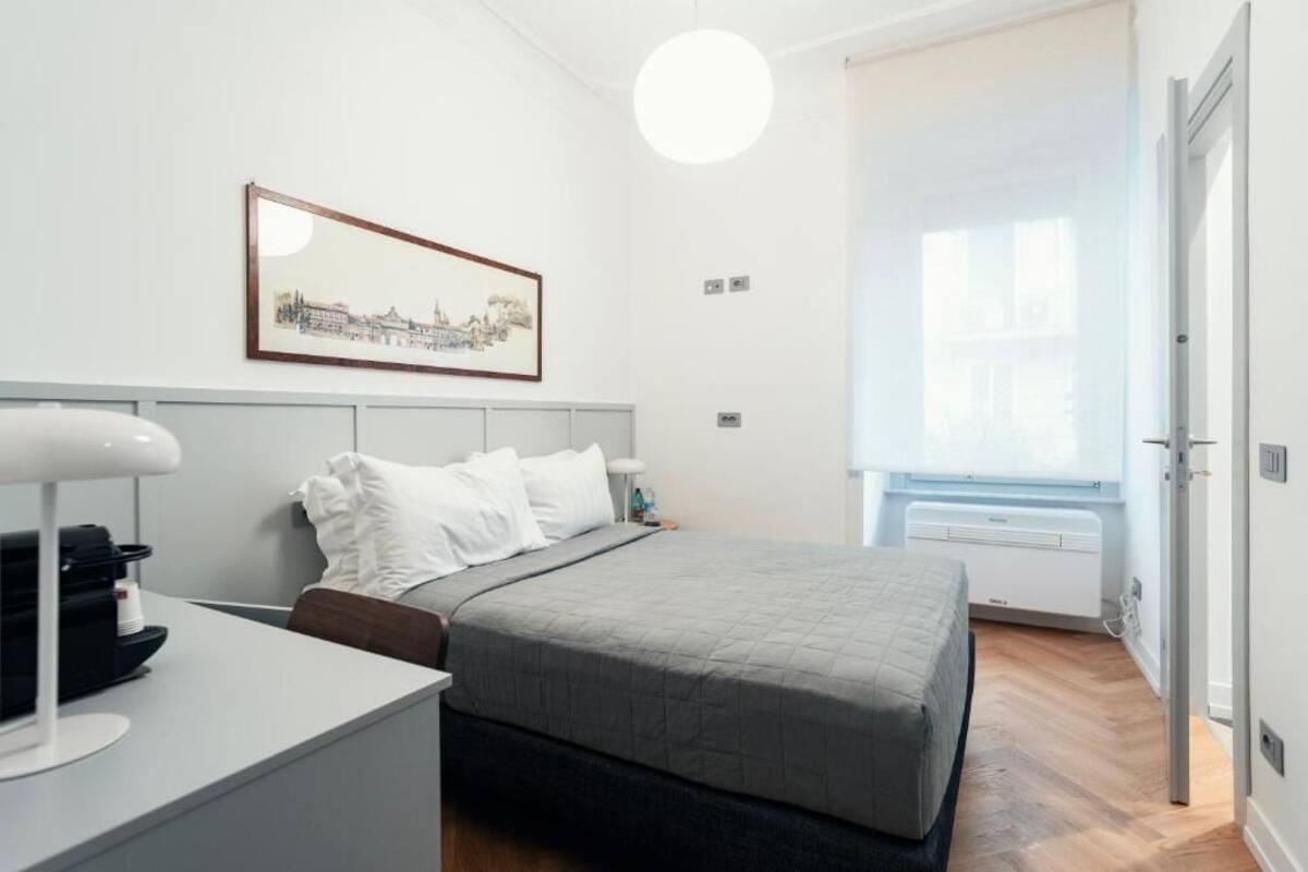 Une chambre d’hôtel moderne avec un lit, une table de chevet et un tableau encadré au mur.