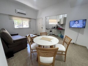 Un espace de vie compact comprenant un coin repas, une kitchenette et un téléviseur.