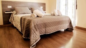 Een opgemaakt bed met een gewatteerde sprei, kussens en opgerolde handdoeken.