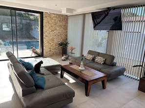 A modern living room with a grey sofa, a wooden coffee table, and a TV mounted on the wall.