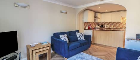 A living room with a blue sofa, a TV, and a small wooden table.
