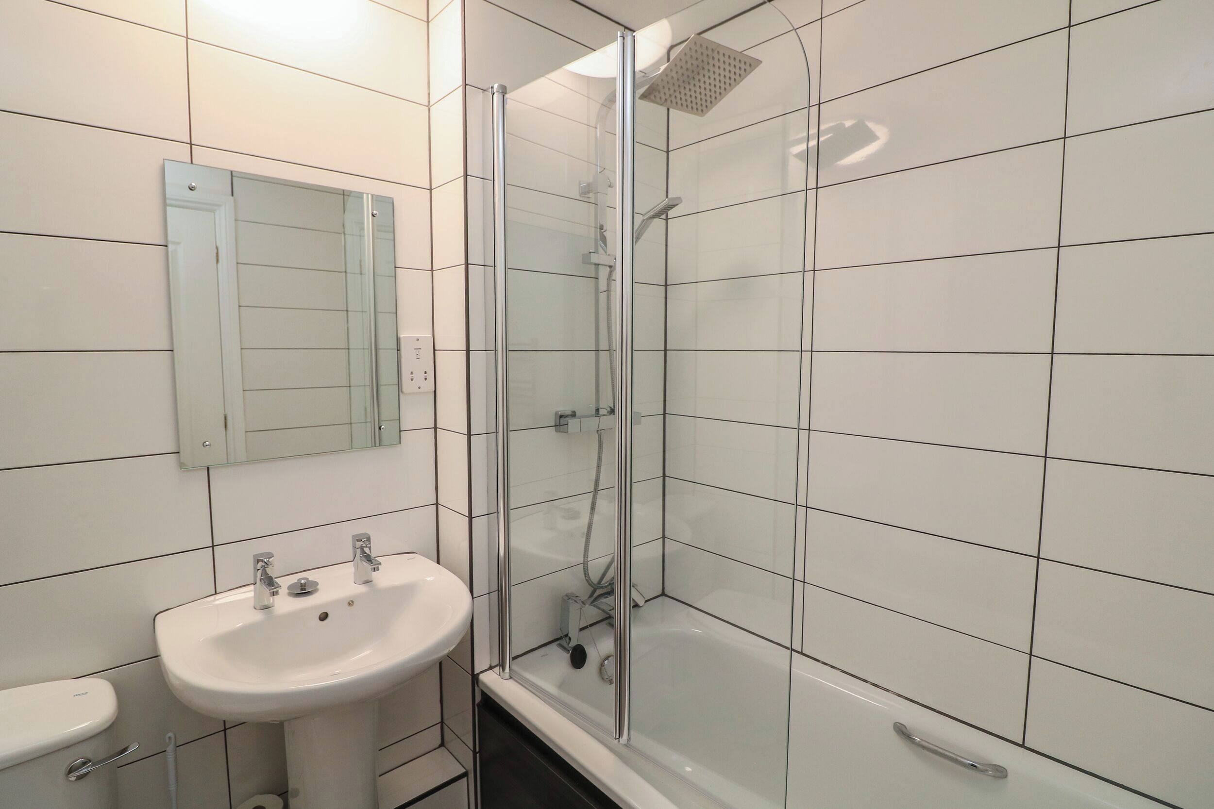 Un baño con ducha de vidrio, lavamanos y retrete.