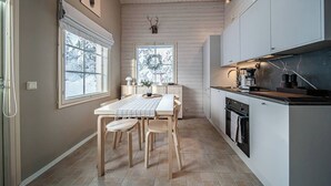 Cocina moderna con comedor, ventanas amplias y vistas a árboles nevados.